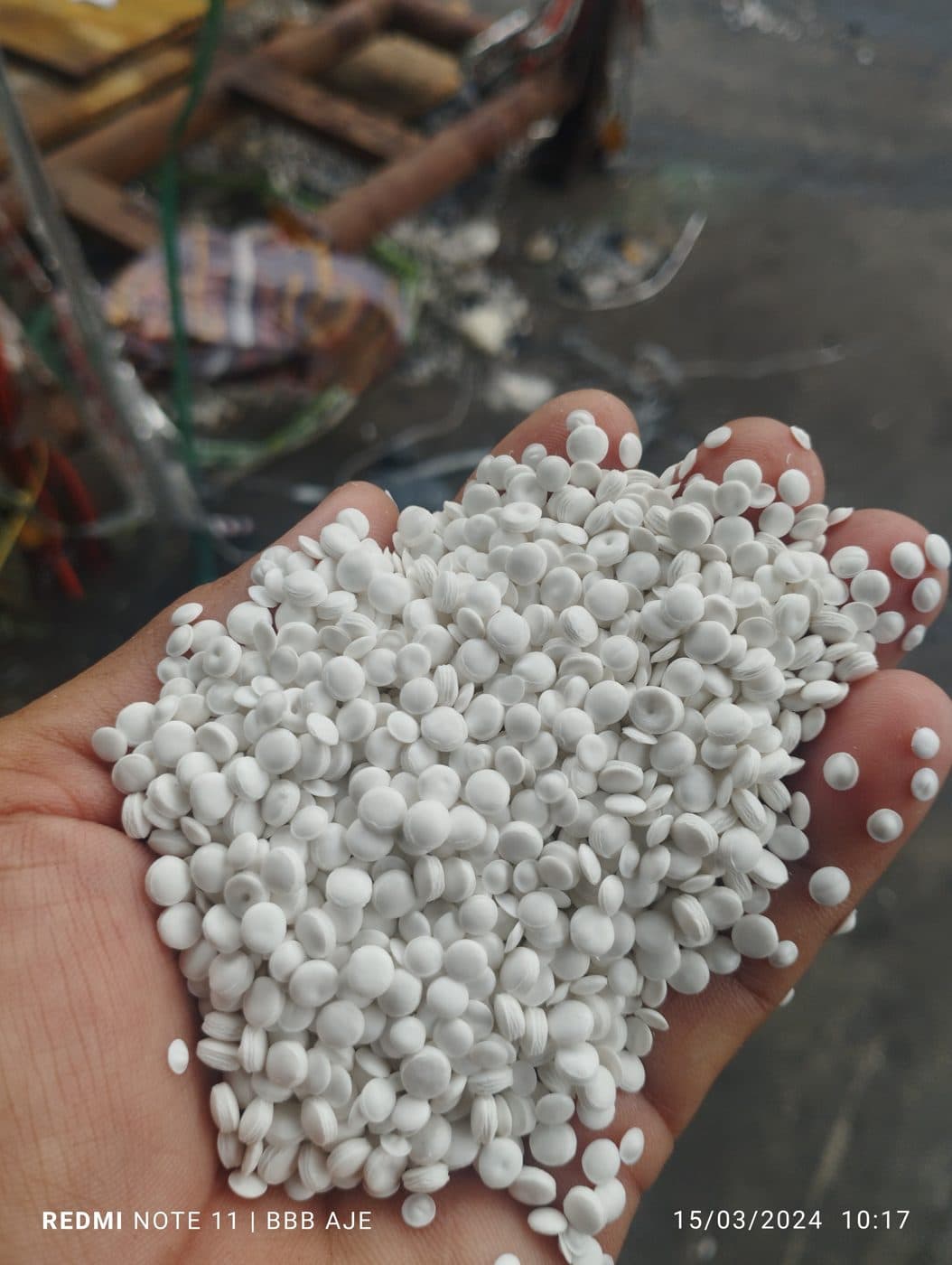 Biji plastik daur ulang warna putih dalam genggaman tangan